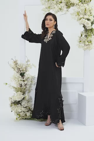 Video of a model in Oriel black festive set moves gracefully through minimalist white studio adorned with floral arrangements and props
