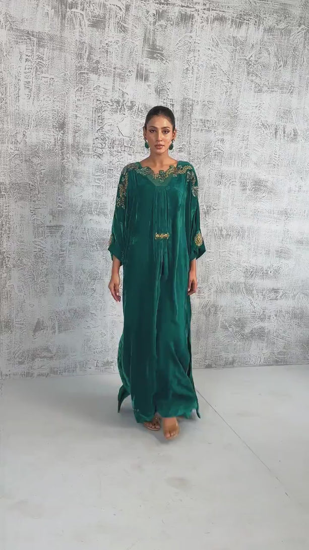 VIDEO: A video showcasing an emerald green silk kaftan with intricate gold embroidery. 

